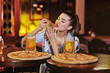 © Evgeniy Kalinovskiy - a young pretty girl eating pizza and drinking beer or a beer citrus cocktail on the background of a bar or pizzeria.