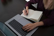 © eskstock - Female designer using laptop, sketching at blank notepad. Woman hand writing in notebook on wooden desk. Concept ease of use of Internet and accessibility of information of working process.