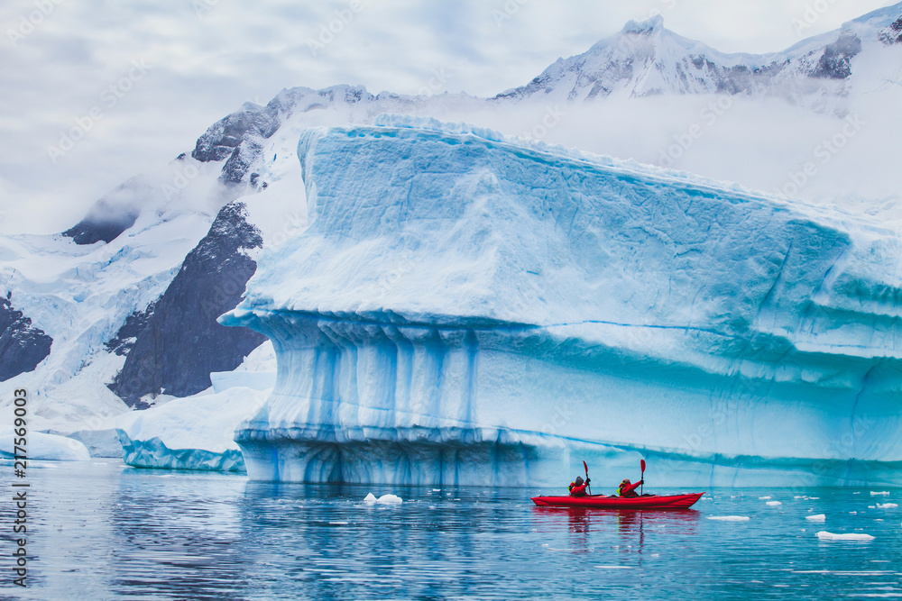 winter kayaking in Antarctica, extreme sport adventure, people paddling on kayak near iceberg - obrazy, fototapety, plakaty 