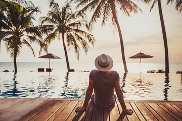 tourist in luxury beach hotel near luxurious swimming pool at sunset, tropical exotic holidays vacation, tourism and travel