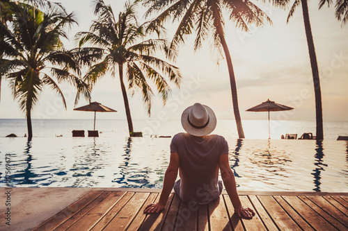 Fotomural tourist in luxury beach hotel near luxurious swimming pool at sunset, tropical e