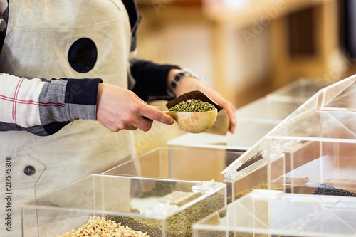 Fotografie, Obraz Saleswoman putting soya in a bulk shopping bag in an organic store