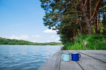 two metal cups with tea. river on background. summer time concept