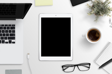 Wall Mural - tablet mockup on office desk surrounded with laptop, glasses, cup of coffee, plant, pencil and paper
