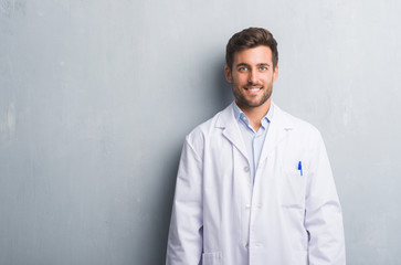 Sticker - Handsome young professional man over grey grunge wall wearing white coat with a happy and cool smile on face. Lucky person.