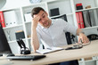 © Ivan Traimak - A young man sits at a table in the office and holds his hand to his head.