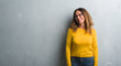 © Krakenimages.com - Middle age hispanic woman over grey wall wearing glasses looking away to side with smile on face, natural expression. Laughing confident.