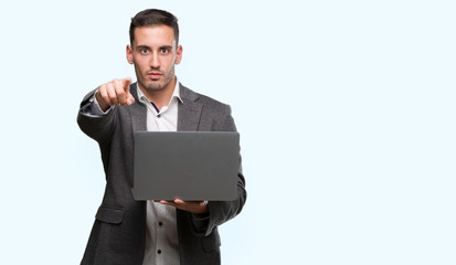 Poster - Handsome young man using computer laptop pointing with finger to the camera and to you, hand sign, positive and confident gesture from the front