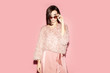 © Sergey Chumakov - fashionable woman in pink clothes and sunglasses looking at camera isolated on pink background