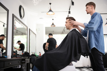 Professional barber working with client in hairdressing salon. Hipster fashion