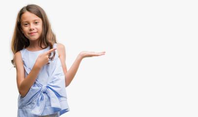 Sticker - Brunette hispanic girl amazed and smiling to the camera while presenting with hand and pointing with finger.