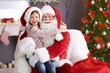 © New Africa - Little girl sitting on authentic Santa Claus' lap indoors