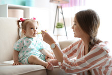 Caring Mother Feeding Her Cute Little Baby With Healthy Food At Home