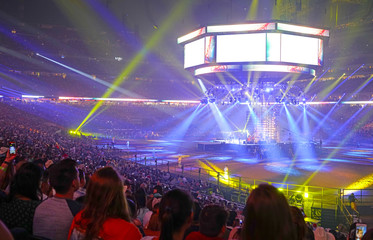 Concert stage with shining lights and crowd at a performance. Rock music event at a stadium with colorful spotlights and projectors.