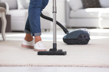 Wall Mural - Woman cleaning carpet with vacuum cleaner, closeup