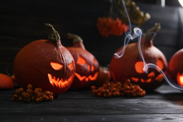 halloween pumpkin lanterns with luminous scary faces on a dark background with the smoke around them