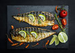 Grilled mackerel fillets with lime on black slate board