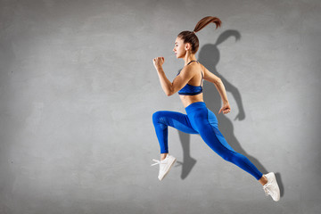 Wall Mural - Sporty young athletic woman runing and jumping.