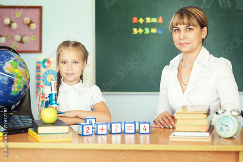 Teacher Helping Schoolgirl With Her Homework In Classroom At School Teacher Helping Schoolgirl With Her Homework In Classroom At School