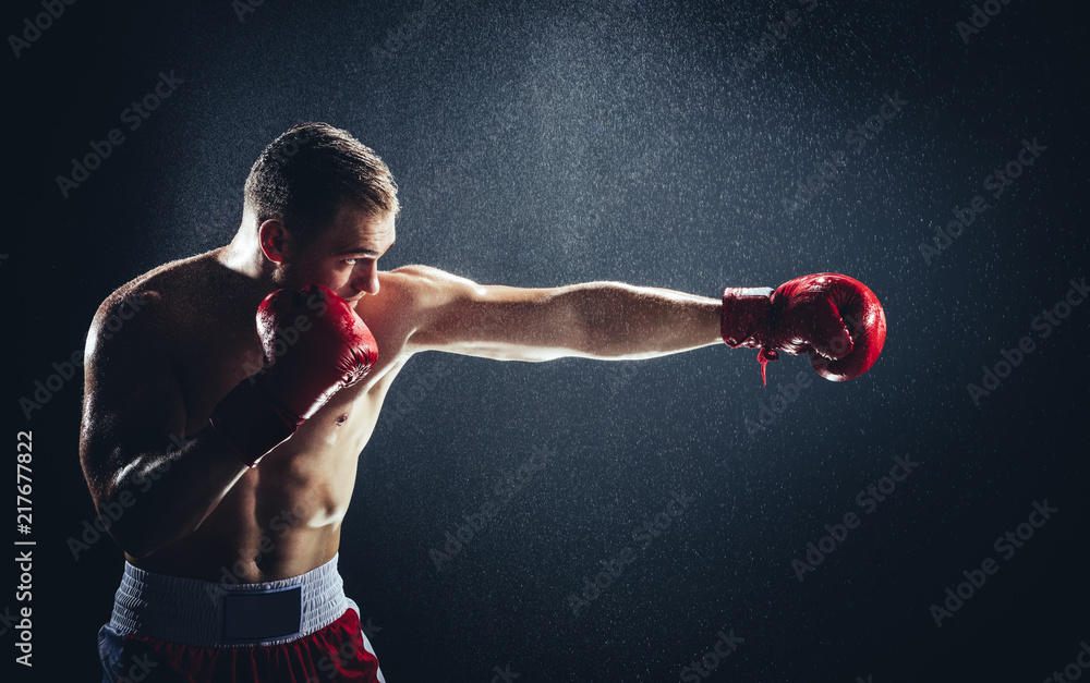 Boxer striking a blow in the rain. - obrazy, fototapety, plakaty 
