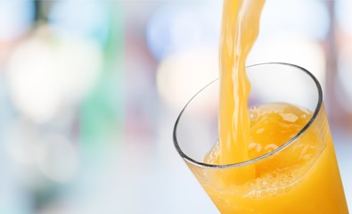 Poster - Orange juice pouring in glass on background