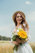 © LIGHTFIELD STUDIOS - portrait of cheerful woman in white dress with bouquet of wild flowers in field