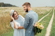 © LIGHTFIELD STUDIOS - smiling man hiding bouquet of wild flowers for girlfriend behind back in summer field