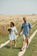 © LIGHTFIELD STUDIOS - woman in white dress with bouquet of wild flowers walking together with boyfriend in field