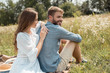 © LIGHTFIELD STUDIOS - smiling couple resting in field with wild flowers on summer day