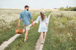 © LIGHTFIELD STUDIOS - rear view of couple with picnic basket holding hands while walking in field