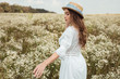 © LIGHTFIELD STUDIOS - pretty pensive woman in straw hat and white dress on meadow with wild flowers