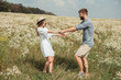 © LIGHTFIELD STUDIOS - side view of cheerful couple holding hands on meadow with wild flowers