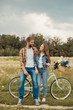 © LIGHTFIELD STUDIOS - smiling lovers with retro bicycle looking at each other in field with wild flowers