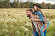 © LIGHTFIELD STUDIOS - happy couple piggybacking together in summer field with wild flowers