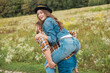 © LIGHTFIELD STUDIOS - happy couple piggybacking together in summer field with wild flowers