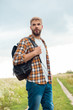 © LIGHTFIELD STUDIOS - portrait of handsome pensive man with black leather backpack looking away in field