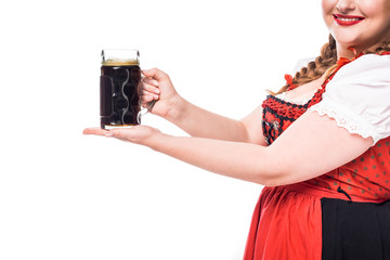 Wall Mural - cropped image of oktoberfest waitress in traditional bavarian dress holding mug of dark beer isolated on white background