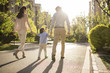 © Blue Jean Images - Happy young family holding hands walking