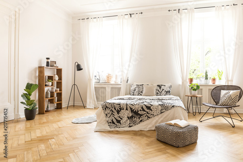 A Big Bed With Linen A Metal And Rattan Chair A Lamp A