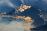 Fototapeta Na sufit - Blue sky with dramatic cloud against orange rays of the sun