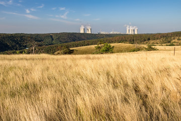 Summer meadow with dry grass and nuclear power plant