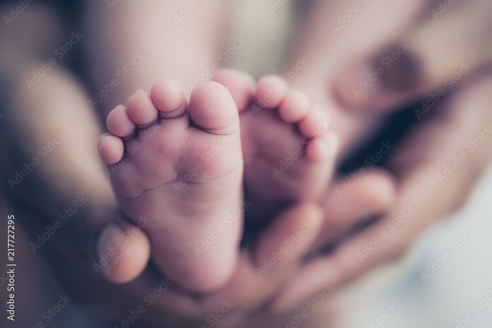 Obraz Feet of a newborn baby in the hands of parents. Happy Family oncept. Mum and Dad hug their baby's legs. fototapeta, plakat