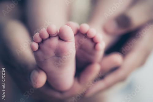Cuadros en Lienzo Feet of a newborn baby in the hands of parents