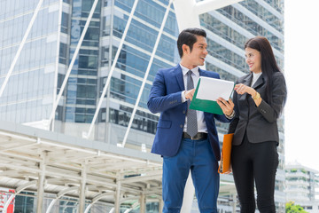 Wall Mural - Asian businessman and businesswoman stand in the city and talk about business success.