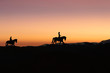 © Alfredo - Silhouette of man and woman riding horse across horizon as the sun goes down