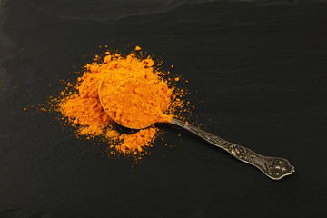 Wall Mural - Metal spoon full of yellow turmeric powder on black