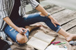 © Cavan Images - Low section of woman studying while sitting on pier in forest