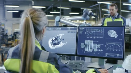 Wall Mural - At the Factory:Female Mechanical Engineer Designs 3D Engine on Her Personal Computer Talks with Male Automation Engineer who Uses Laptop for Programming Robotic Arm