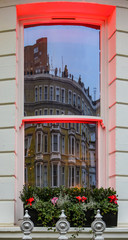 Wall Mural - London - Yellow building with bay windows reflected in a window across the street with dramatic red lighting on sills and a window box filled with flowers