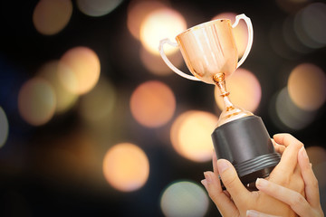 Wall Mural - winner hold trophy with abstract bokeh light background